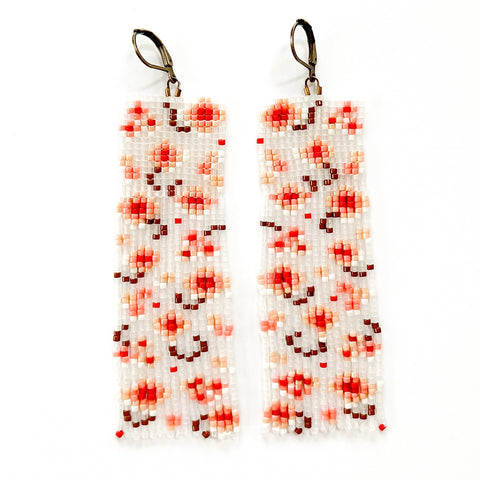 A pair of handmade earrings with translucent glass seed beads featuring a pink and red floral patten.