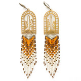 A pair of beaded earrings with browns and creams woven onto a brass cactus charm, photographed on a white background.